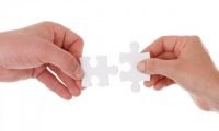 dwie ręce układające dwa puzzle